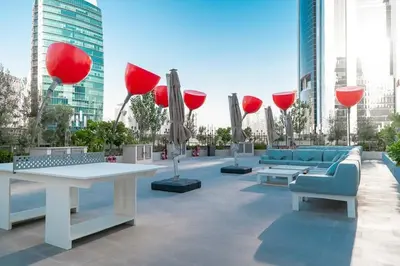 a patio with couches and tables and red umbrellas at Frank Porter - MAG 318 in Dubai