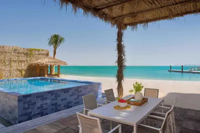 a patio with a table and a swimming pool on the beach at Anantara World Islands Dubai Resort in Dubai