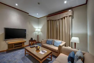 a living room with a couch and a flat screen tv at Orchid Hotel Al Barsha 