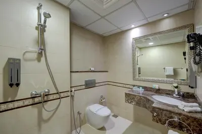 a bathroom with a toilet and a sink and a mirror at Orchid Hotel Al Barsha 