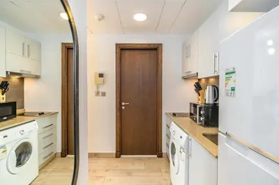 a kitchen with white cabinets and a washer and dryer at Silkhaus studio in DIFC with Burj Khalifa view, pool & gym in Dubai