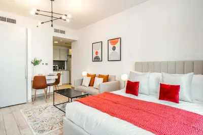 a bedroom with a large white bed with red pillows at Silkhaus studio in DIFC with Burj Khalifa view, pool & gym in Dubai