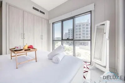 a white bedroom with a large white bed and a table at Peaceful 1BR at MAG 505 Dubai South by Deluxe Holiday Homes in Dubai