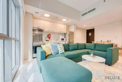 a living room with a blue couch and a kitchen at Peaceful 1BR at MAG 505 Dubai South by Deluxe Holiday Homes in Dubai