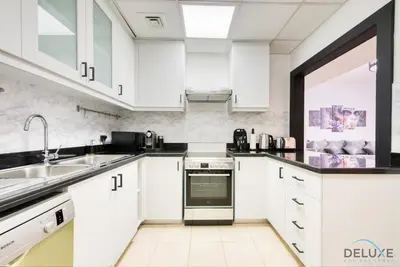 a kitchen with white cabinets and a sink at Elegant 2BR at Bahar 2 JBR by Deluxe Holiday Homes in Dubai