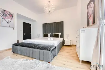 a bedroom with a large bed and a chandelier at Elegant 2BR at Bahar 2 JBR by Deluxe Holiday Homes in Dubai