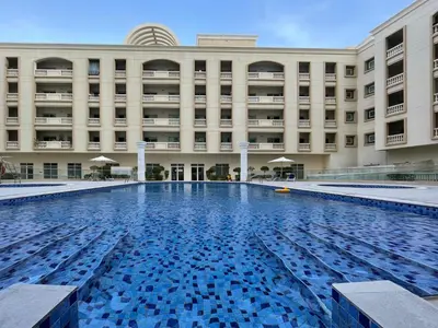 a large building with a swimming pool in front of it at The Smart Concierge - Plaza residences in Dubai
