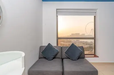 a couch with two pillows in a room with a window at Elan Rimal 5 Suites in Dubai