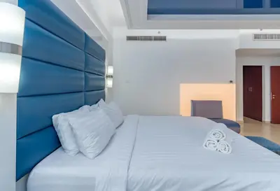 a bedroom with a white bed with a blue headboard at Elan Rimal 5 Suites in Dubai
