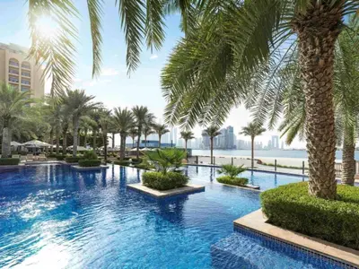 a swimming pool with palm trees in a resort at Fairmont Apartments The Palm, Free access to hotel beach and pools in Dubai