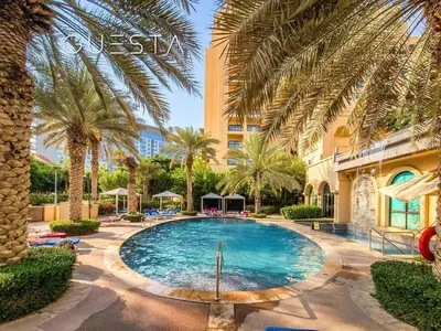 a swimming pool with palm trees and a building at Fairmont Apartments The Palm, Free access to hotel beach and pools in Dubai