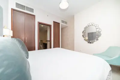 a bedroom with a white bed and a blue chair at BellaVista - Sophisticated - 2 BR - 29 Boulevard - Burj Khalifa & Fountain View in Dubai