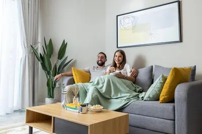 a man and woman sitting on a couch in a living room at Unlock Waters Edge in Dubai