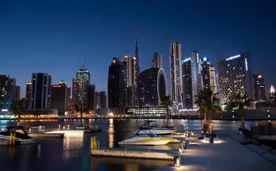 a city skyline at night with boats in the water at Unlock Waters Edge in Dubai