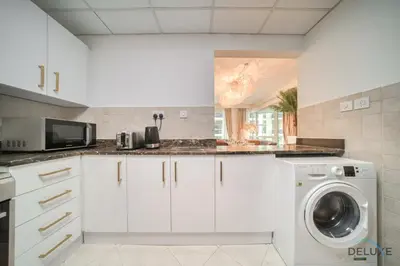 a kitchen with white cabinets and a washer and dryer at Classy 2BR at La Riviera Dubai Marina by Deluxe Holiday Homes in Dubai