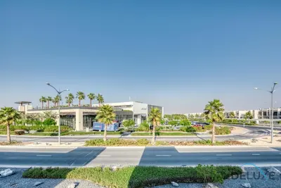 a street in front of a building with palm trees at Extensive 3BR Townhouse at Janusia Damac Hills 2 by Deluxe Holiday Homes in Dubai