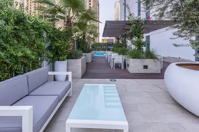 a patio with a couch and tables and plants at LIV Residence, Dubai Marina in Dubai