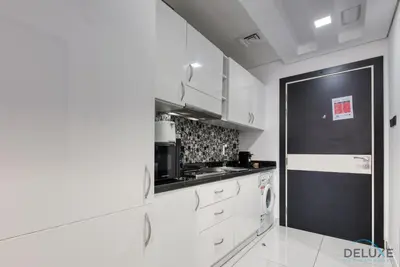 a kitchen with white cabinets and a black door at Radiant Studio at Giovanni Boutique Suites DSC by Deluxe Holiday Homes in Dubai