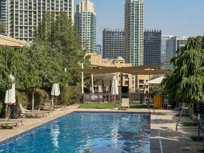 a swimming pool with chairs and umbrellas in a city at Durrani Homes - Arabian luxury at Souk Al Bahar besides Burj Khalifa & Dubai Mall in Dubai
