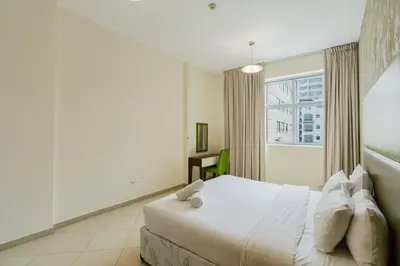 a white bedroom with a bed and a window at RH- Convenient 1BR, Central, Walk to Mall of Emirates, Al Barsha1 in Dubai