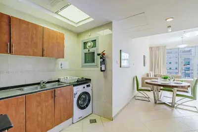 a kitchen with a washing machine and a table at RH- Convenient 1BR, Central, Walk to Mall of Emirates, Al Barsha1 in Dubai