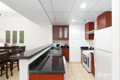 a kitchen with brown and white cabinets and a counter top at Dream Inn Apartments - Rimal JBR in Dubai