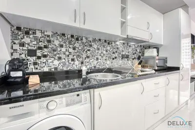 a kitchen with a sink and a washing machine at Captivating Studio at Giovanni Boutique Suites DSC by Deluxe Holiday Homes in Dubai