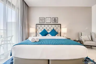 a bedroom with a large bed with blue pillows at Restful Studio at Celestia A Dubai South by Deluxe Holiday Homes in Dubai