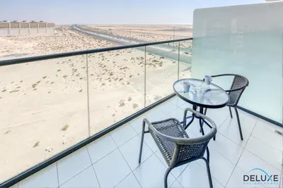 a glass table and two chairs on a balcony with a beach at Restful Studio at Celestia A Dubai South by Deluxe Holiday Homes in Dubai
