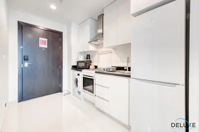 a kitchen with white cabinets and a black door at Restful Studio at Celestia A Dubai South by Deluxe Holiday Homes in Dubai