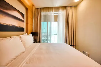 a bedroom with a large white bed with a window at Emaar Fashion Avenue one bedroom - Formerly Address Dubai Mall Four Apple Holiday Homes in Dubai