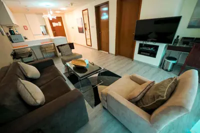 a living room with two couches and a tv at Emaar Fashion Avenue one bedroom - Formerly Address Dubai Mall Four Apple Holiday Homes in Dubai