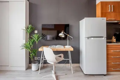 a kitchen with a desk and a white refrigerator at Silkhaus renovated studio with Burj Khalifa view in DIFC in Dubai