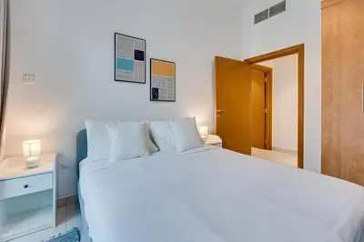 a bedroom with a white bed and a wooden door at Great views from New apartment in Dubai Marina in Dubai