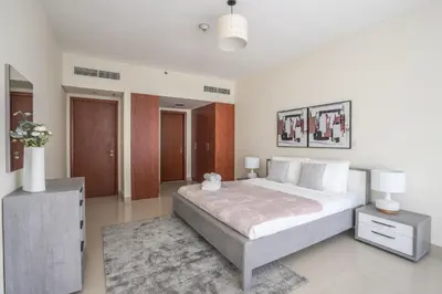 a white bedroom with a large bed and a rug at HiGuests - Luxury Apartment in the Iconic Park Towers in Dubai