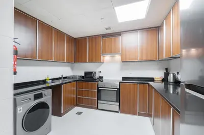 a kitchen with wooden cabinets and a washer and dryer at Trinity Holiday Homes - Sheikh Zayed Road Right Next to Financial Center Metro Station Exit 1 in Dubai