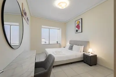 a bedroom with a bed and a chair and a mirror at Trinity Holiday Homes - Sheikh Zayed Road Right Next to Financial Center Metro Station Exit 1 in Dubai