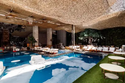 a swimming pool with white chairs and tables at Ramee Dream Hotel Downtown in Dubai