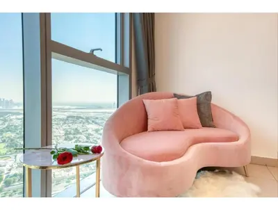 a pink chair in a room with a large window at THE PENTHOUSE near Burj Khalifa and Dubai Mall in Dubai