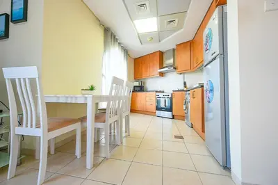 a kitchen with a table and chairs and a refrigerator at Luxury Escapes - Studio near Ibn Battuta Mall & Metro - MOG 193 Discovery Gardens in Dubai