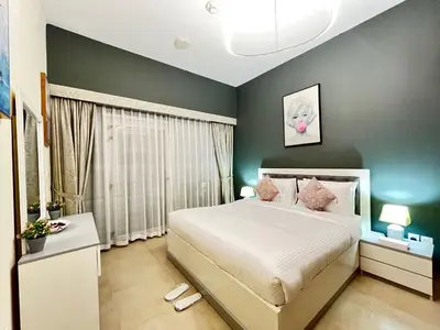 a bedroom with a large white bed and green walls at Trinity Holiday Homes - Spacious Modern Living 1BR & 2BR Unique Apartment in Dubai
