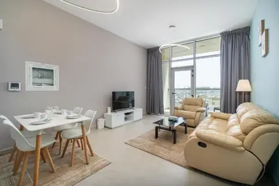 a living room with a couch and a table and a dining room at Trinity Holiday Homes - Spacious Modern Living 1BR & 2BR Unique Apartment in Dubai