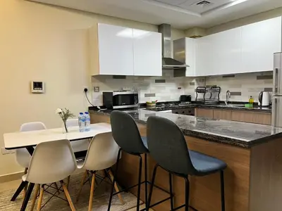 a kitchen with a counter with chairs and a table at Trinity Holiday Homes - Spacious Modern Living 1BR & 2BR Unique Apartment in Dubai