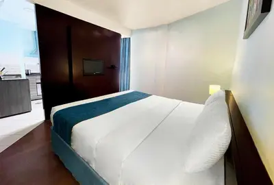 a bedroom with a white bed and a television at Signature Hotel Apartments and Spa in Dubai