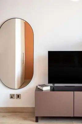 a living room with a mirror and a tv at Silkhaus modern studio with Burj Khalifa view in DIFC in Dubai