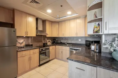 a kitchen with wooden cabinets and a stainless steel refrigerator at HiGuests - Spacious Apartment Close to Dubai Marina Walk in Dubai