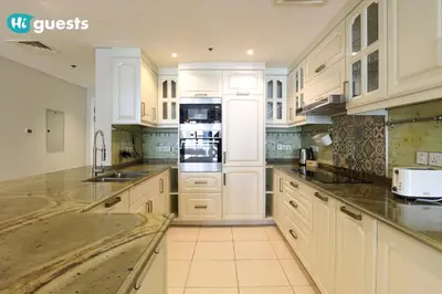 a large kitchen with white cabinets and appliances at HiGuests - Royal 2BR Apt with Maid's Room Near Burj Khalifa in Dubai