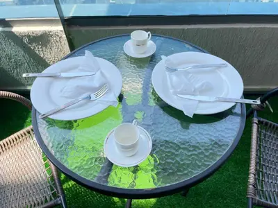 a glass table with plates and utensils on it at Luxury Room with Marina view close to JBR Beach and Metro with Shared Kitchen in Dubai