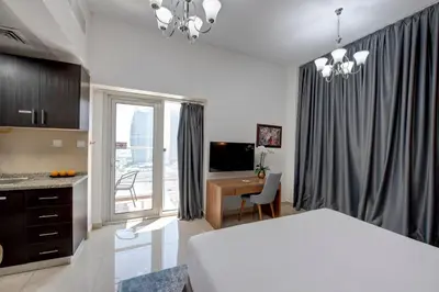 a bedroom with a white bed and a desk and a window at Regency Luxury Suites in Dubai