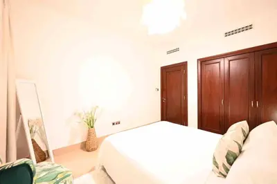 a white bedroom with a bed and a wooden cabinet at Brand new furniture . Close to Dubai Mall. in Dubai